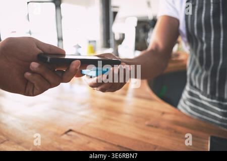People, hands and cashier with pos machine or phone for payment, checkout or scan on counter. Customer, barista and tap to pay with mobile smartphone Stock Photo