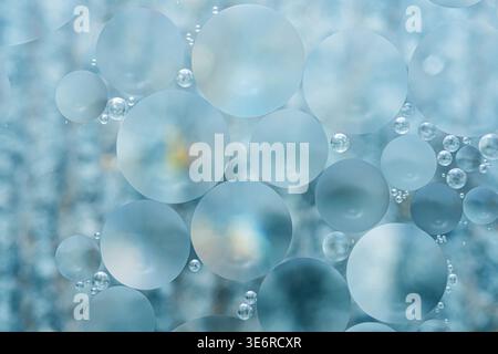 Blue oil droplets merging and separating in water, creating ethereal abstract patterns of soft textures, circles and translucent gradients. Photograph Stock Photo