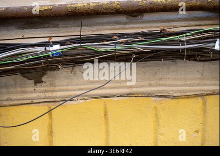 Multiple black and green data wires running along an exterior facade in an urban environment. Concept of network installation, broadband connectivity, Stock Photo