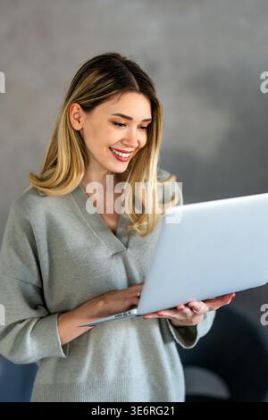 Young female designer, freelancer working in the office. Female using laptop to searching info. Stock Photo
