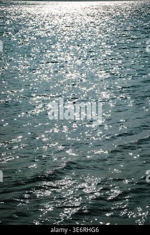 Sunlight reflecting on rippling water surface creating bright highlights across open sea or lake during daytime Stock Photo
