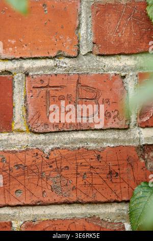 Brick wall, letter and stone with writing on concrete building structure for memory or imprint. Empty, vandalism and graffiti with rectangle blocks Stock Photo