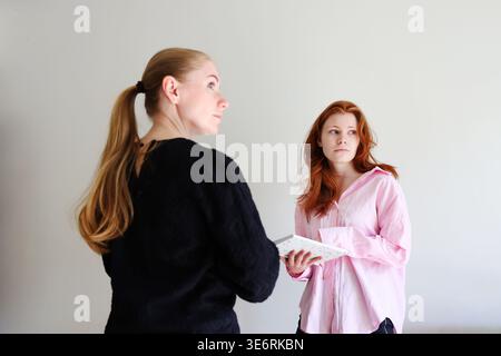 Collaboration between two women reviewing notes, teamwork and business communication concept. Stock Photo