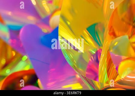 Bright iridescent holographic texture with vibrant pink, orange and yellow colors. Abstract background photography showing colorful light reflections, neon gradients and creative aesthetic ripples. High quality photo Stock Photo