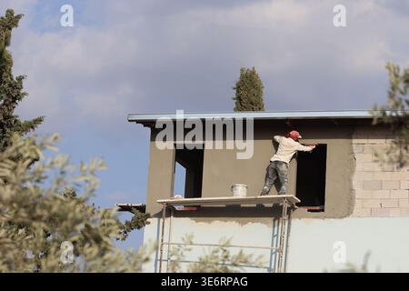 Plasterer working on a scaffold without any safety belt Stock Photo