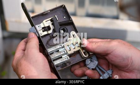 Person hands holding an open door lock mechanism with keys to show its internal structure and components. Stock Photo