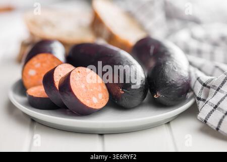 Smoked blood sausage sliced and arranged on a white plate with rustic bread and a checked kitchen towel, highlighting rich color, savory texture and t Stock Photo