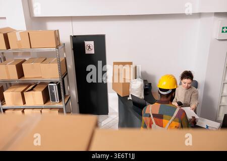Diverse coworkers discussing merchandise packaging details before start working at customers orders in warehouse. Stockroom employees planning merchandise inventory, analyzing products checklist Stock Photo
