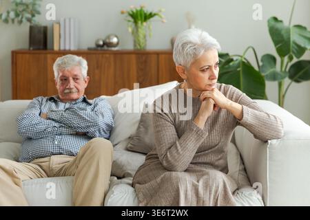 Marriage crisis relationship problems. Old couple quarreling. Sad mature disappointed woman sitting away from husband after having quarrel. Senior couple not talking having problems in relationship Stock Photo