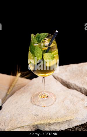 Mojito cocktail, mint, lime slices and ice cubes on a dark background. Cocktail mojito, ice tongs and cocktail spoon on slate board. Copy space Stock Photo