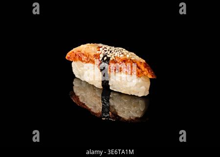 Single grilled unagi eel nigiri sushi with nori, white rice and sesame seeds isolated on black background with mirror reflection. Part of nigiri sushi Stock Photo
