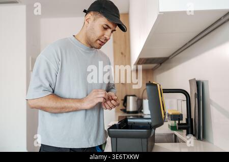 Skilled Technician Employs Multimeter And Notes To Identify Electrical Problems In Contemporary Kitchen Stock Photo
