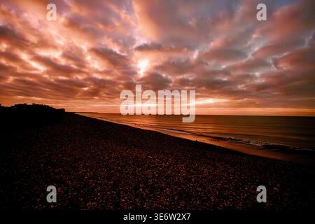 Dramatic stormy sunset over shingle beach and sea Stock Photo