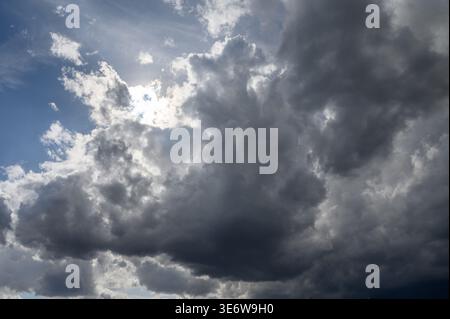 High-resolution photo of a stormy sky, featuring dense, dark clouds typical of stormy or rainy weather. The image highlights the dramatic contrast and Stock Photo