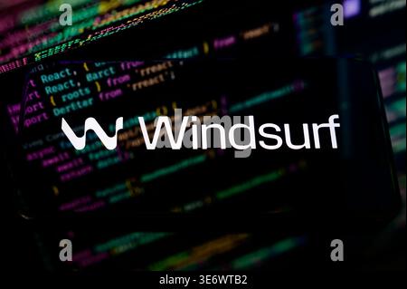 Paris, France - April 1, 2026: Logo of Windsurf AI, a next-generation agentic IDE for developers, displayed on a phone with code in the background. Stock Photo