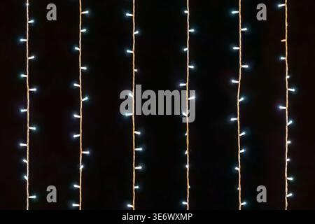 Seamless pattern of vertical glowing blue fairy lights on a black background. Repeatable festive light texture ideal for large scale holiday banners Stock Photo