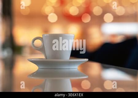 Cup of coffee and multicolored defocused bokeh lights background with copy space for text. Glimmering lights reflecting on tabletop, blurry background Stock Photo