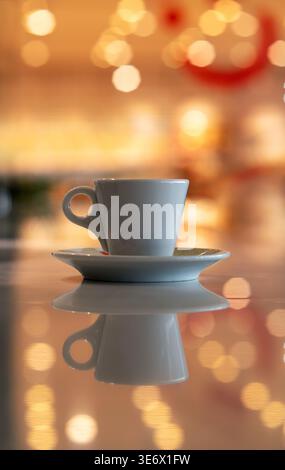 Cup of coffee and multicolored defocused bokeh lights background with copy space for text. Glimmering lights reflecting on tabletop, blurry background Stock Photo