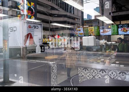 Reflections of a street crossing, menu boards, a counter and the interior of a fast food restaurant are seen through a large window near Yonge Dundas Stock Photo