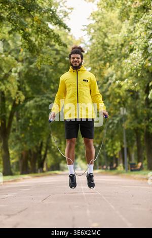 Young man in a yellow windbreaker jumps rope outdoors on a lovely spring morning. Stock Photo