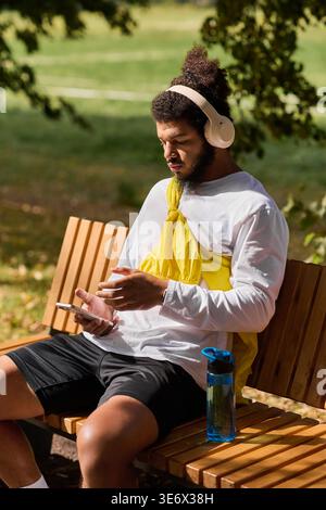 African american man in headphones resting on bench outdoors, enjoying spring. Stock Photo