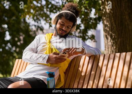 A young Black man in headphones using his phone on a spring day. Stock Photo