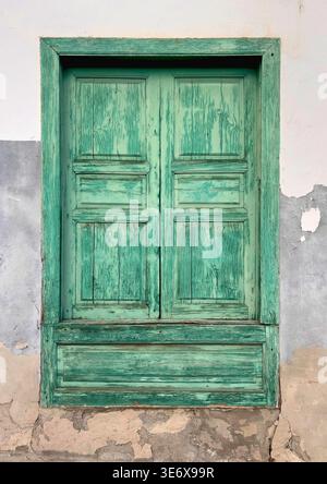 Old painted wooden window shutters showing texture and decaying paint on a rustic wall Stock Photo