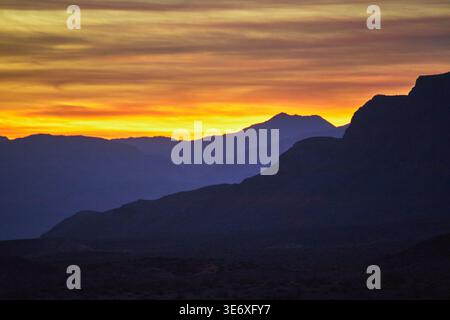 Sunrise Mountain Silhouettes and Colorful Sky Over Desert Valley Landscape Stock Photo