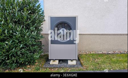 Gray air conditioning unit installed outdoors next to concrete wall Stock Photo
