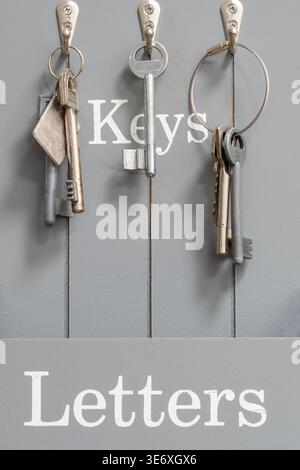 Keys hanging on hooks with gray labeled storage board Stock Photo