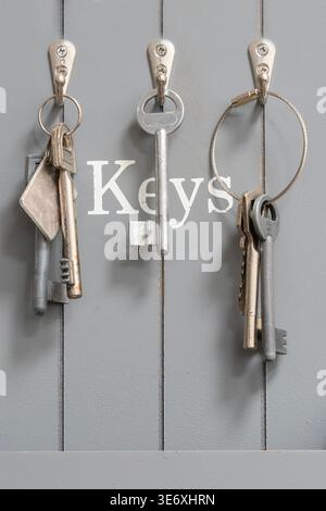 Keys hanging on hooks with gray labeled storage board Stock Photo