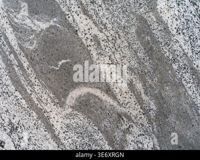 Detailed macro shot of a highly textured grey granite stone surface featuring a dense mix of dark speckles and dramatic flowing vein patterns. The sce Stock Photo