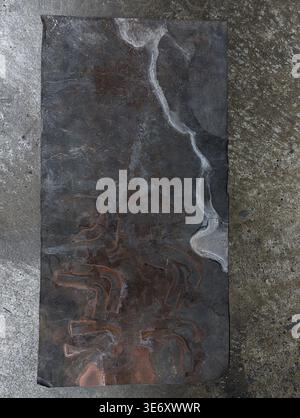 Dark Metal Slab With Marbled Patina, Material Sample Resting On Rough Concrete, Visible Oxidation Veins And Worn Edges Texture Study For Restoration O Stock Photo