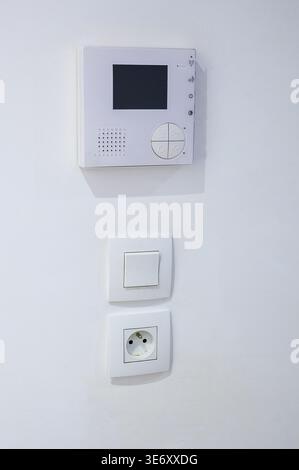 Modern white intercom system and electrical outlets mounted on a clean wall Stock Photo