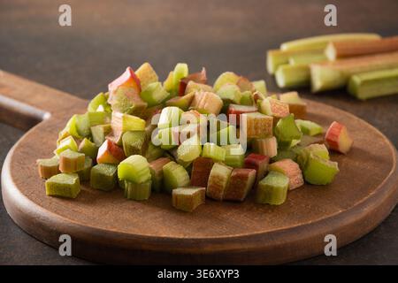 Closeup of chopped rhubarb pieces on wooden board. Fresh organic ingredient for cooking, baking and healthy diet with natural rustic food styling Stock Photo