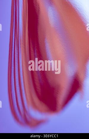 View of a blurred red fabric with soft textures and flowing lines against a cool blue background, Dronten, Flevoland, Netherlands. Stock Photo