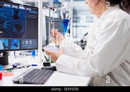 Chemist conducting pipetting operation for petri dish sample analysis in controlled laboratory environment. Research facility employee using pipette for chemical compound evaluation Stock Photo