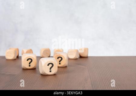 Question marks on wooden blocks with blurred cubes. FAQ, uncertainty and problem solving concept. Stock Photo