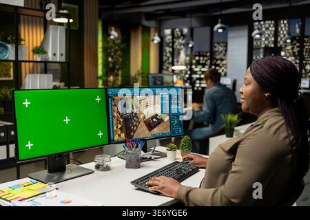 African american architectural specialist using chroma key and CAD program to create a modern apartment, 3D render interface and mockup on dual monitors. Architectural software design. Stock Photo