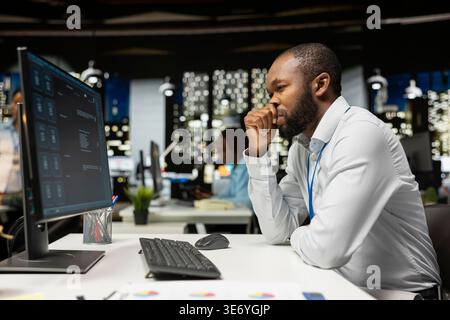 Black worker uses AI chatbot system at desktop for problem solving tasks, futuristic technology highlighting smart algorithms and machine learning. Communication and IT support. Stock Photo