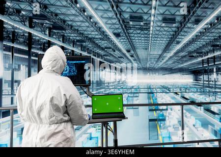 Green screen tablet, monitoring autonomous robotics and engineer in AI semiconductor factory. Using artificial intelligence, mockup device and expert enhancing productivity of industrial plant Stock Photo