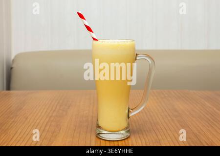 A striking tall, glossy glass overflowing with fresh orange juice, revealing tiny bubbles and floating pulp in the morning light Stock Photo