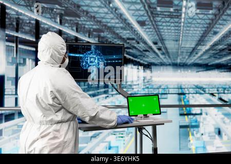 Green screen tablet used by engineer in semiconductor factory monitoring autonomous robotics with AI. Expert uses artificial intelligence and mockup device to enhance productivity of industrial plant Stock Photo