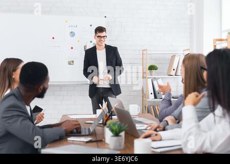 Director showing presentation on flipchart to his staff Stock Photo