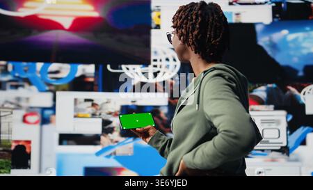 Isolated screen mobile phone used by person to look at internet video channels, isolated over digital backdrop. Woman enjoying unlimited metaverse video content using chroma key smartphone, camera A Stock Photo