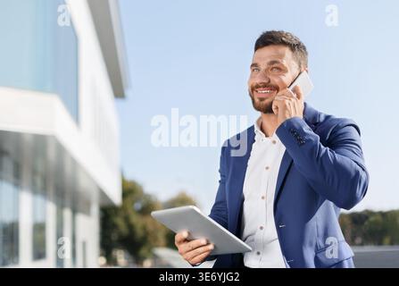 Businessman working on tablet and talking on phone Stock Photo