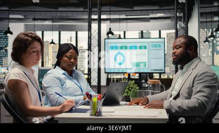 HR team conduct CV evaluation with candidate during job interview in a business space, analyzing work experience and qualifications for career development. Talent acquisition. Camera A. Stock Photo