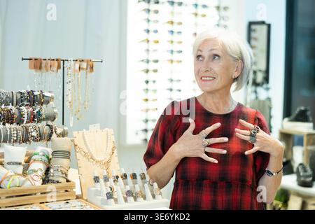 Delighted elderly lady admiring costume jewelry in trendy store Stock Photo