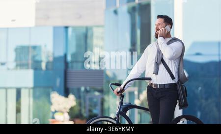 Smiling businessman talking over mobile phone standing with bicycle Stock Photo