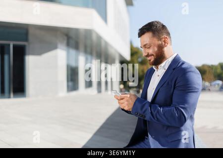Businessman using mobile phone app outside at office Stock Photo